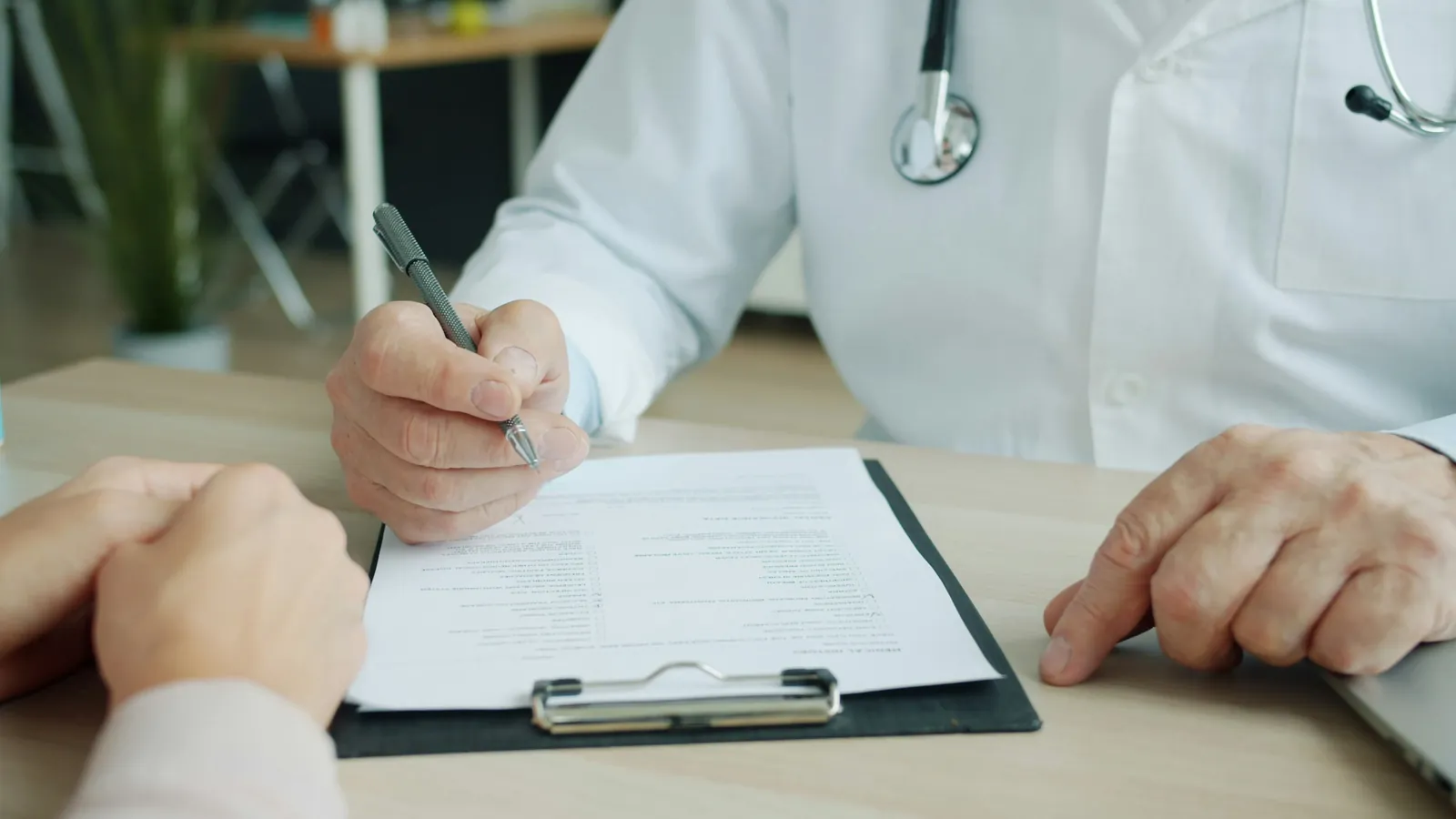 Medic urolog completează fișa unui pacient în cabinet